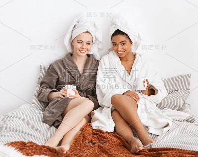 穿着浴袍坐在床上喝着咖啡的漂亮女友