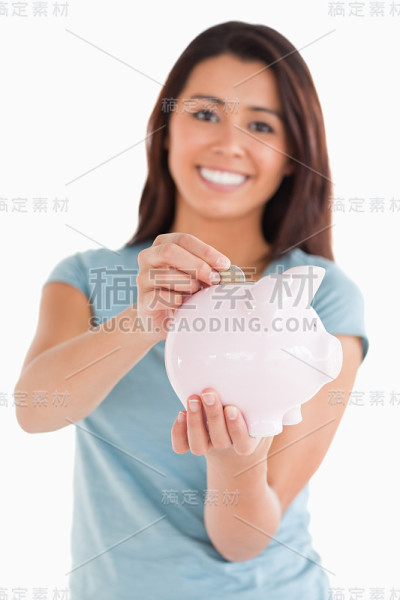 可爱的女人把一枚硬币放进存钱罐