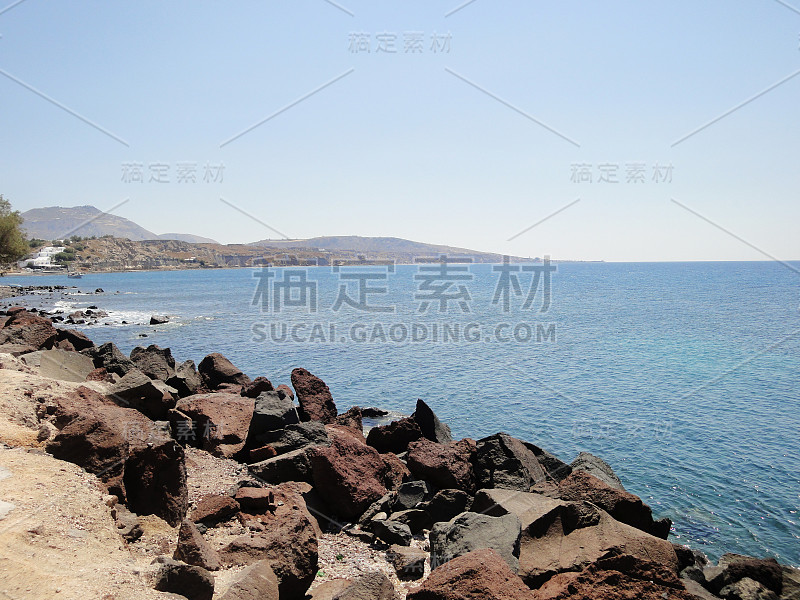 在希腊圣托里尼岛，岩石海岸景色与平静的大海和蓝天