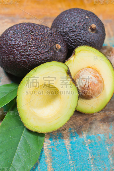 蓝色的木桌上放着新鲜成熟的鳄梨