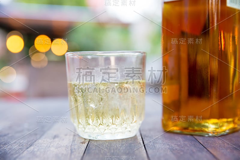 靠近酒杯，酒瓶在木桌上，散景灯光和模糊的背景。一起出去聚会。酒精和聚会。