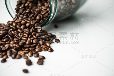 从玻璃瓶里洒下的咖啡豆洒在白色