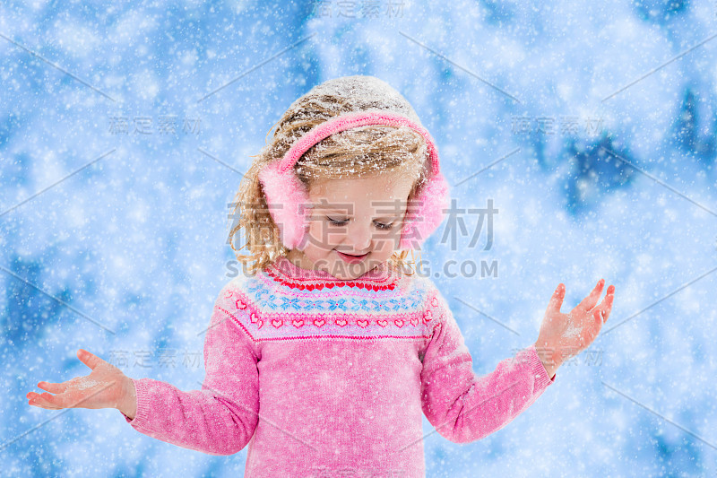 小女孩在冬天的公园里捕捉雪花