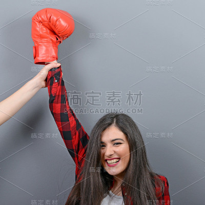 灰色背景下，裁判手握女子拳击冠军的手。