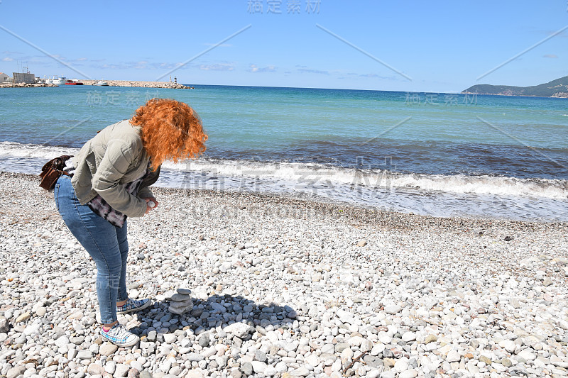 女人在海滩上建造石塔