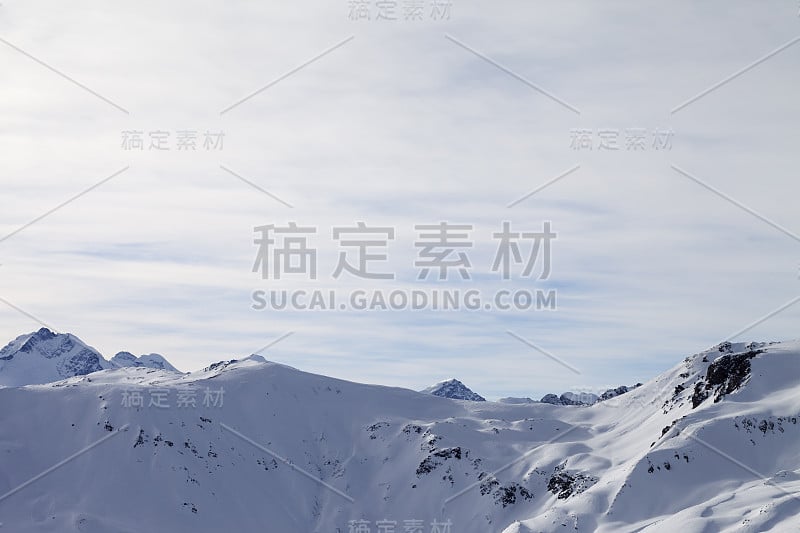 冬季高山的雪坡和早晨阳光明媚的多云天空