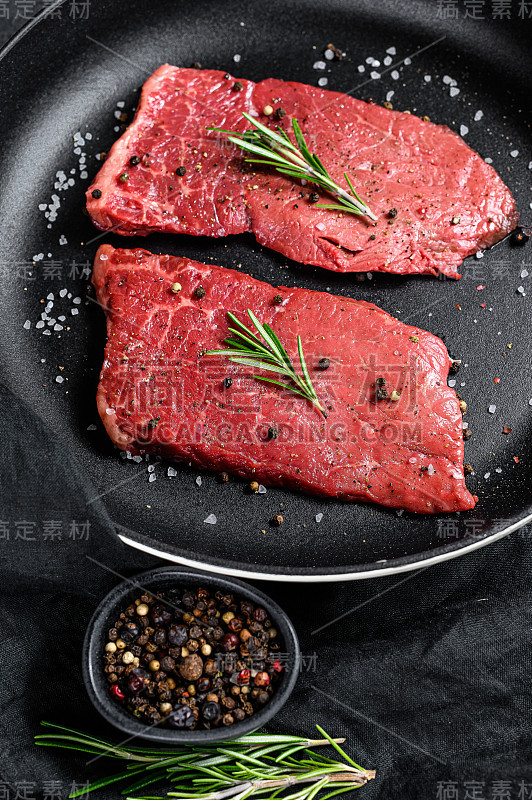 煎锅里的生西冷牛排。牛肉的肉。黑色背景。俯视图