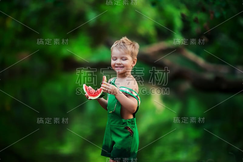 绿色的夏日照片，一个小男孩站在湖里吃着一片西瓜