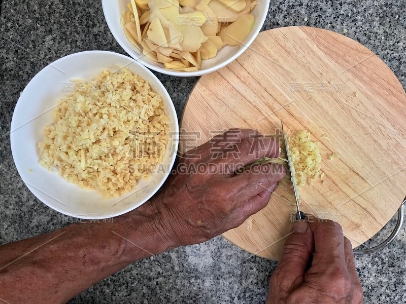 男子用菜刀和木砧板切姜