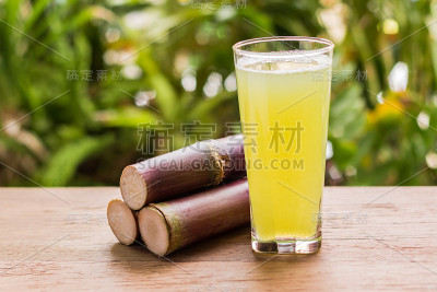 甘蔗汁与一块甘蔗在木制背景