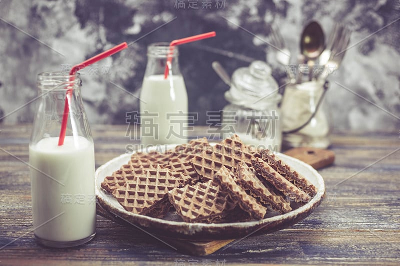 木质背景上的巧克力华夫饼和牛奶玻璃。简单的早餐。糖果