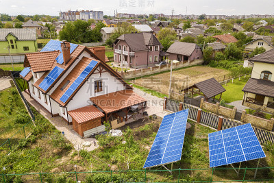 新现代住宅别墅的空中俯瞰，屋顶上有蓝色闪亮的太阳能光伏电池板系统。可再生生态绿色能源生产理念。