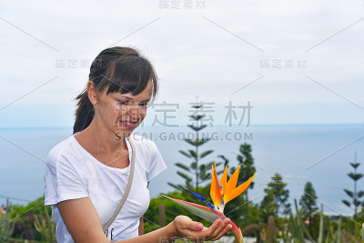 拿着斯特莱丽扎花的年轻女子