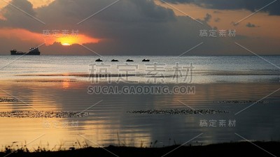 温暖的夕阳颜色在水和远处的船的轮廓。