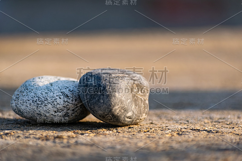 日出时，灰色的柏油路面上铺着两大块光滑的鹅卵石，上面有点点图案。