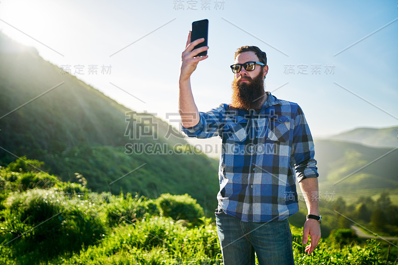 一名蓄着胡须的男子在加州的绿草山前自拍