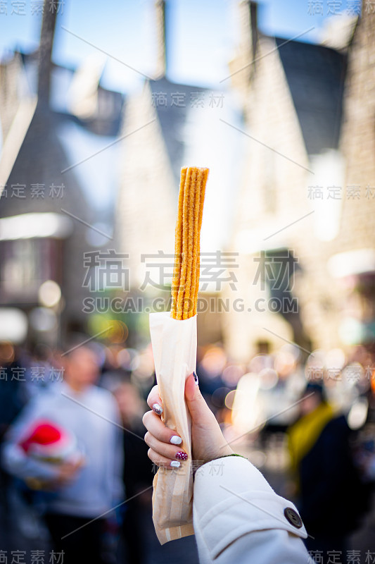 西班牙油条-传统的西班牙甜点手持与背景拷贝空间。