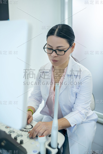 女医生戴着眼镜坐在超声波装置前，神情严肃