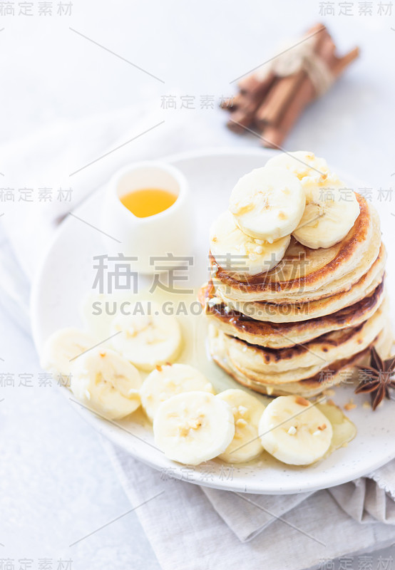 烤饼配香蕉、蜂蜜和坚果放在陶瓷盘子里。完美的早餐。