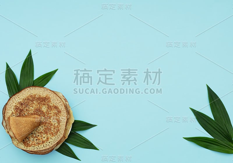 蓝底绿叶自制煎饼。Maslenitsa，春节的概念。俄罗斯的传统食品。煎饼。美味的早餐。平铺风格与复