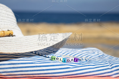 假日度假夏日海滩背景。以蓝色大海为背景的沙滩上的帽子和地毯