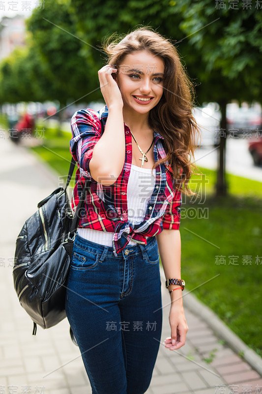 街道肖像美丽的年轻女子走在城市街道与背包