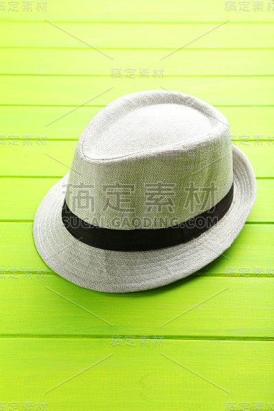 漂亮的白色帽子放在绿色的木桌上