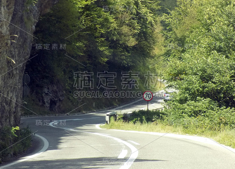 弯弯曲曲的山路上有岩石和限速路标