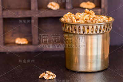 一个木盒背景上的一个铜制罐子里的核桃