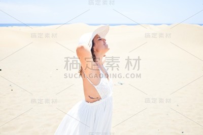 年轻美丽的女人日光浴张开双臂享受夏天在马斯帕洛马斯沙丘海滩