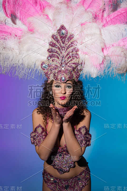 穿着狂欢节服装的女子用粉色羽毛送飞吻
