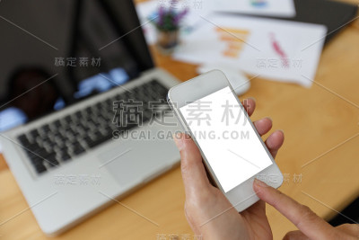 商务女性在木桌上使用智能手机和笔记本电脑