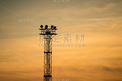 夕阳背景下金属塔上的街灯
