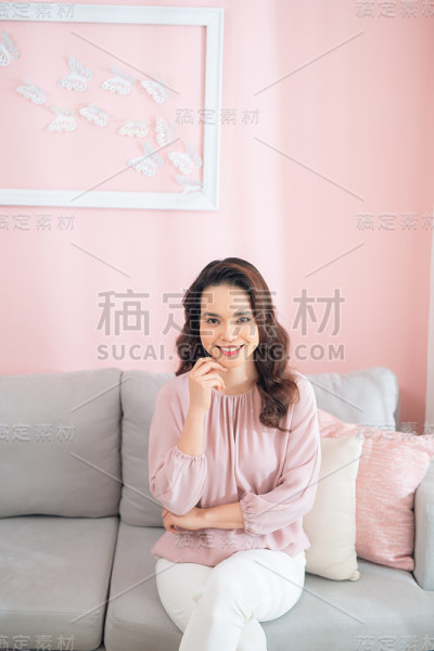 一个亚洲女人坐在沙发上大笑和微笑的肖像。