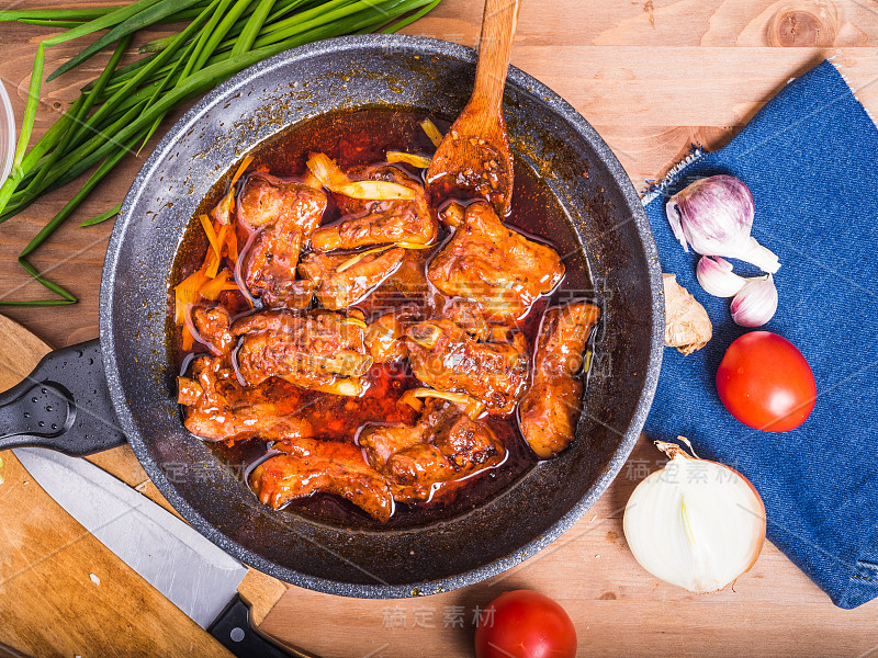 糖醋排骨在一个大锅上与食材一起煮，俯视图。辣卤肉