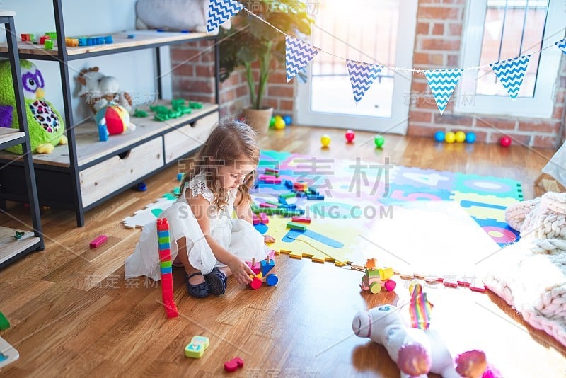 可爱的金发幼童在幼儿园玩火车玩具