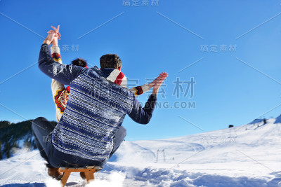 一对年轻夫妇在阳光明媚的冬日里玩雪橇