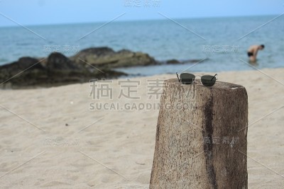 热带海滩上的木制太阳镜:选择浅景深对焦。