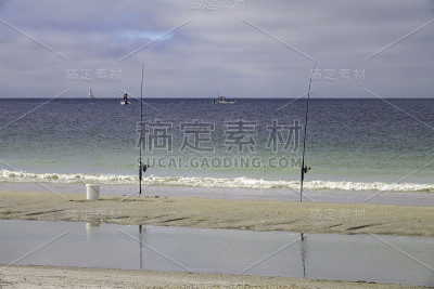 一对鱼竿直立在沙滩上