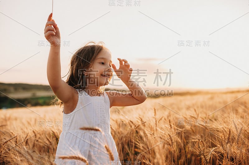 微笑的白人女孩穿着白色的裙子走在麦田里，带着愉快的微笑跳跃