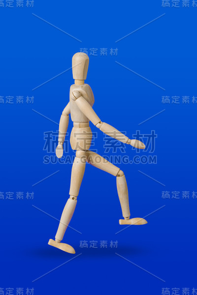 行走的木制玩具人物在蓝色