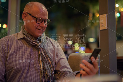 高级游客男子在泰国曼谷考山路夜间使用手机的肖像
