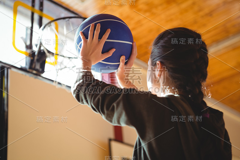 年轻女子在球场上练习篮球的侧视图