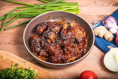 准备好的糖醋排骨放在盘子里与配料一起上桌烹饪，俯视图。桌上放着一份麻辣红烧肉。