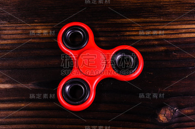 木制书桌上的红色纺纱玩具。俯视图