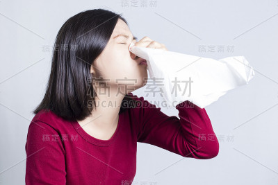 生病的女人对着纸巾打喷嚏