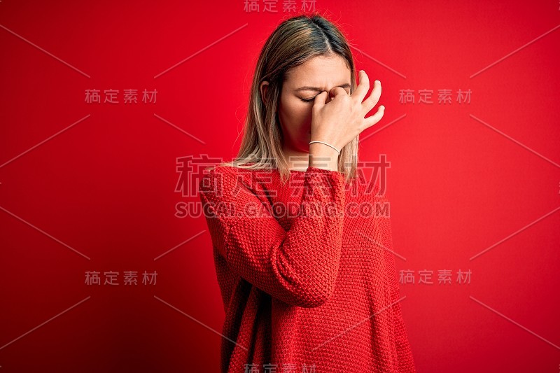 年轻美丽的金发女人穿着休闲毛衣在红色孤立的背景疲劳摩擦鼻子和眼睛感觉疲劳和头痛。压力和挫折的概念。