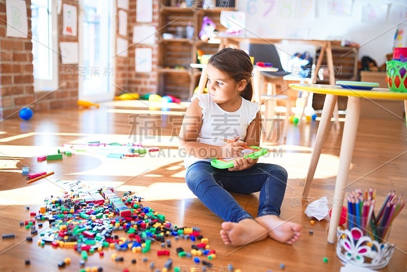 可爱的蹒跚学步的孩子在幼儿园用数字板画很多玩具