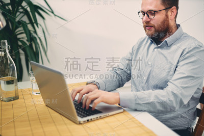年轻的男建筑师坐在他的办公桌前打字。