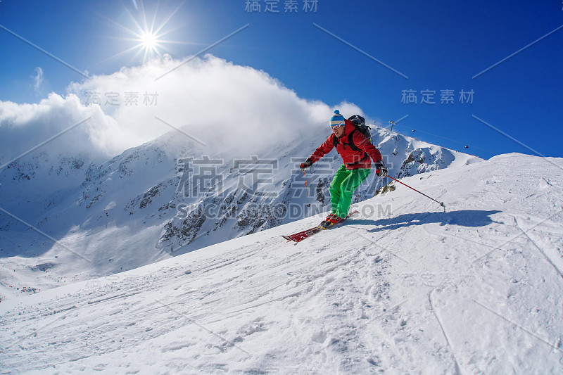 在夕阳的映衬下，滑雪者从高山上往山下滑雪